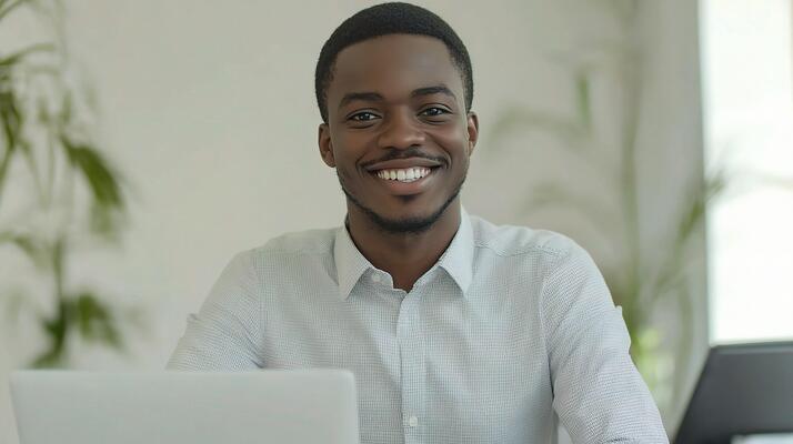 Home a smiling black man with a laptop in front of him free photo